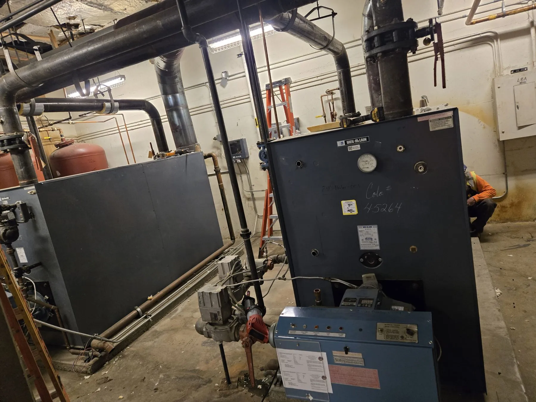 Two-boiler plant in a school mechanical room before demolition