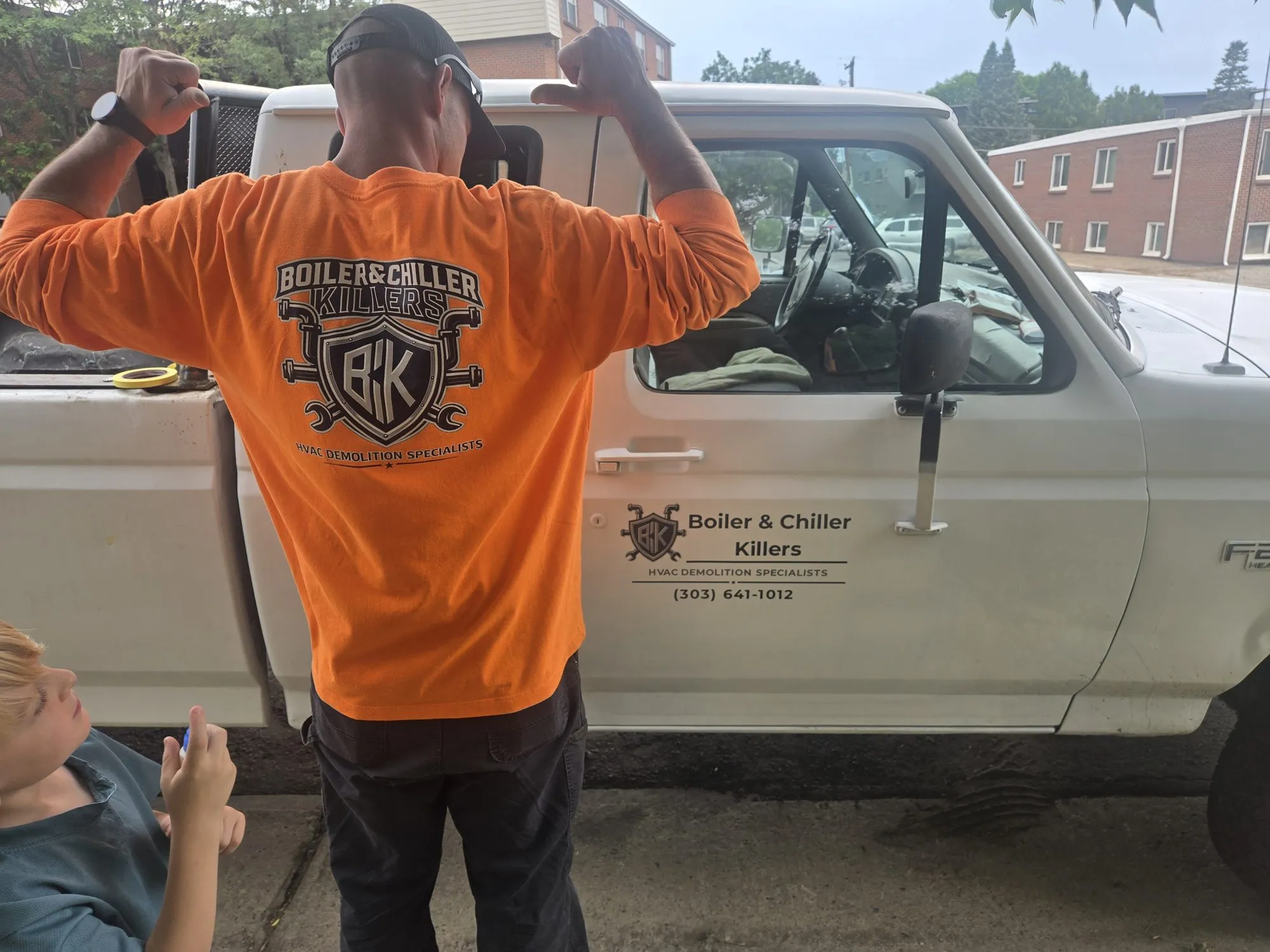 Gadge in front of the BCK work truck with a young family member looking on