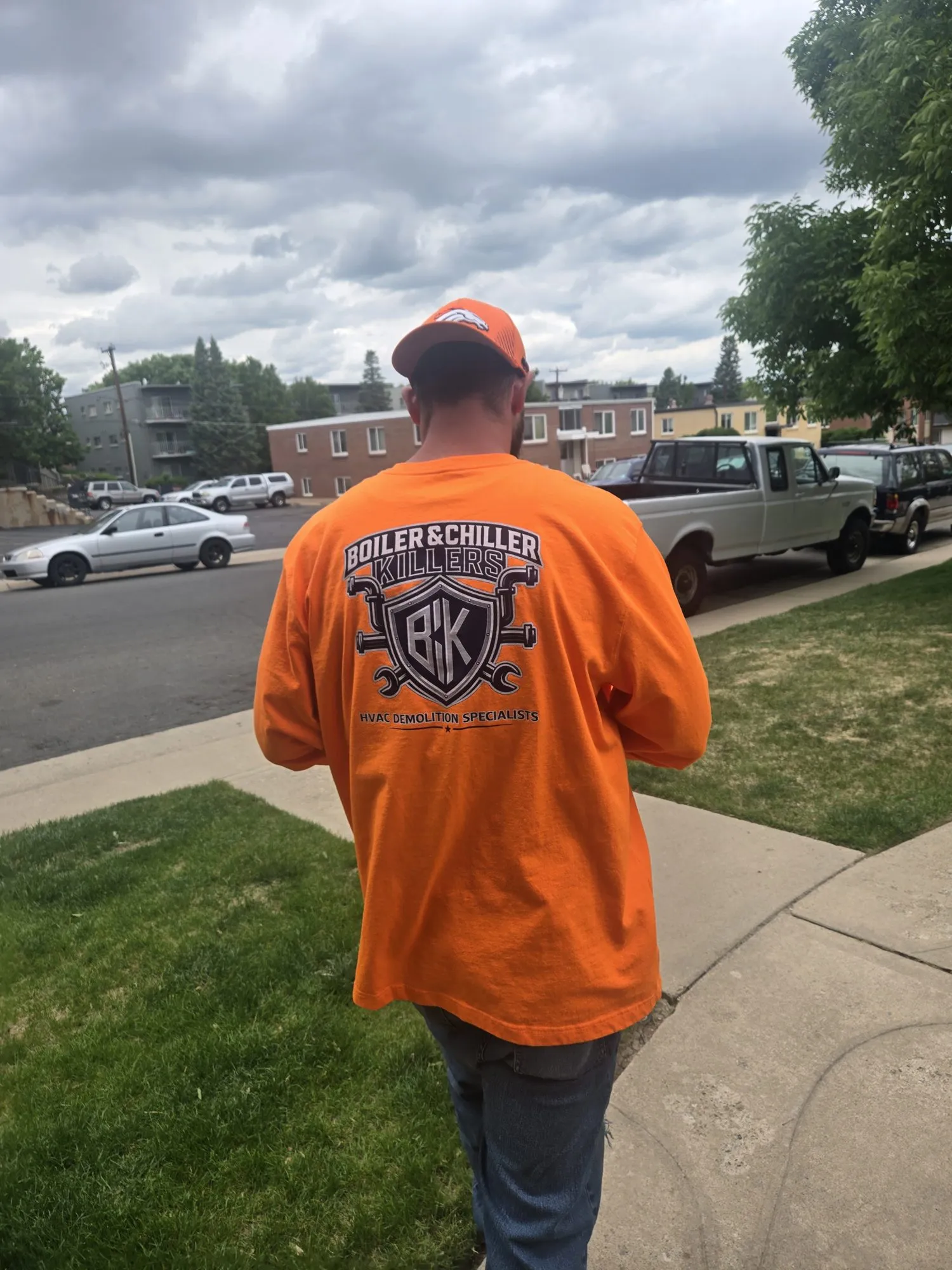 Gadge walking away from the camera in a BCK logo shirt on a job site