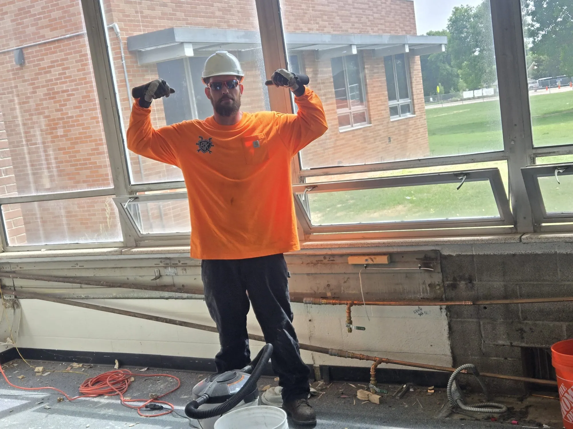 Gadge Bell in a hard hat and BCK shirt on a demolition site