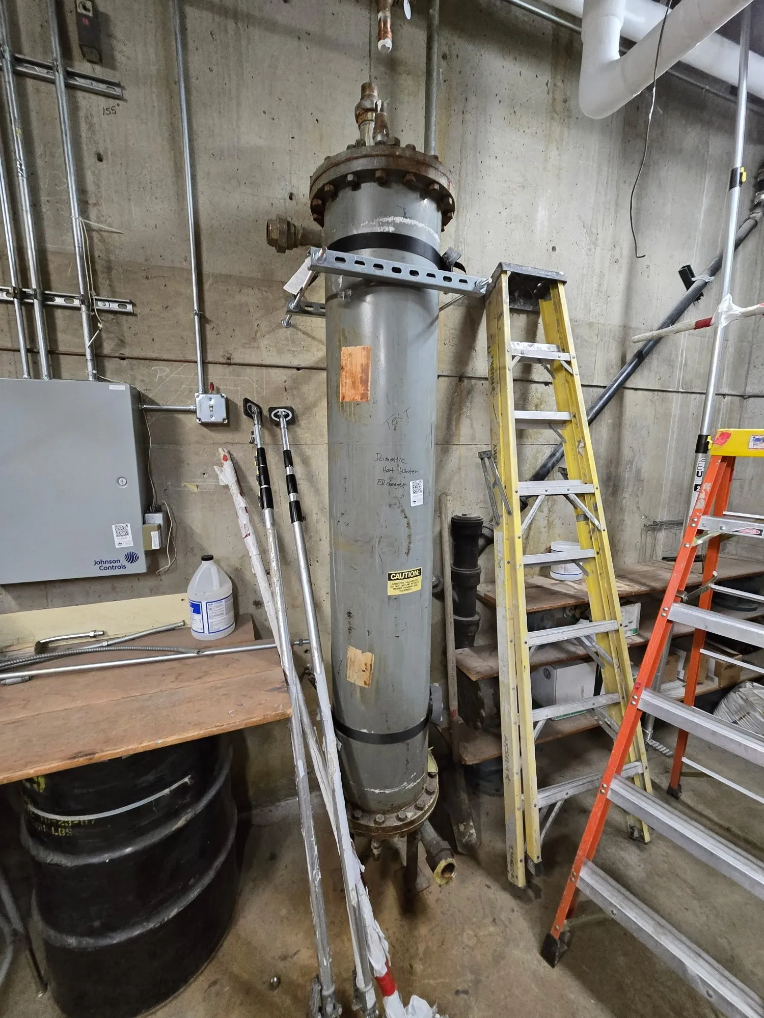 School mechanical room packed with expansion tanks and piping before a strip-out